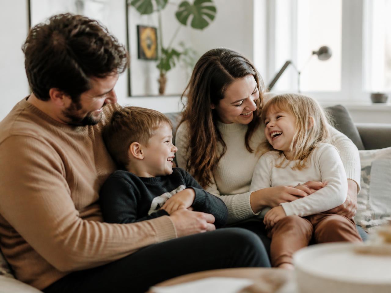 A family laughing together on the couch at home